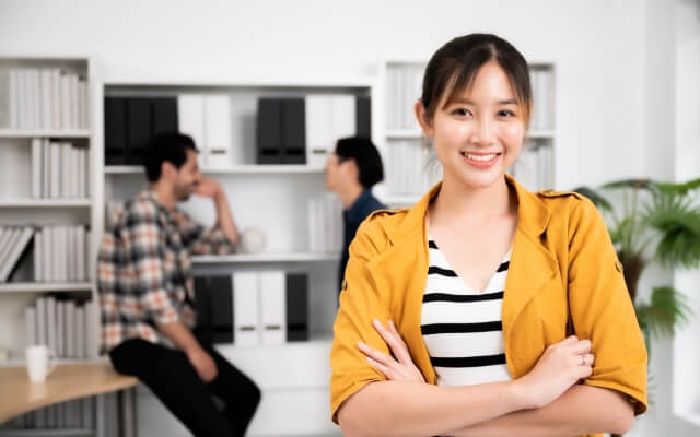 黄色の上着を着た腕を組んでいる笑顔の女性